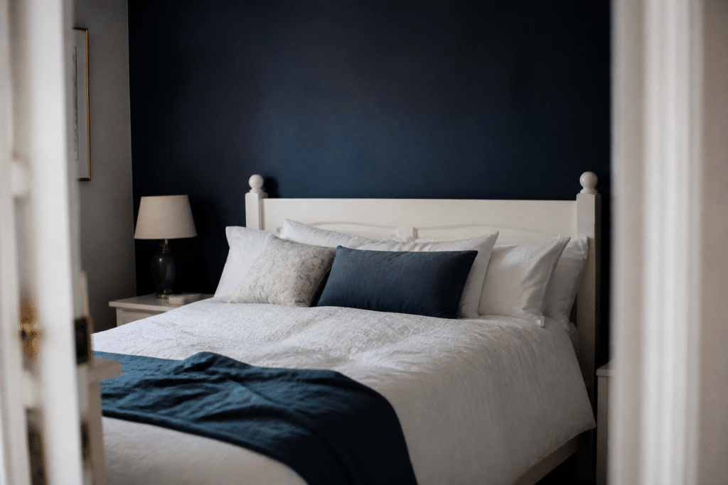 Chambre avec mur bleu foncé derriere lit blanc casse