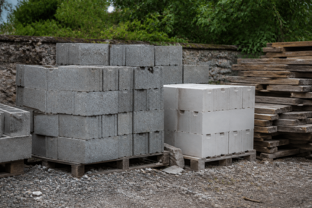 Blocs de parpaing gris, béton cellulaire blanc et planches bois empilés