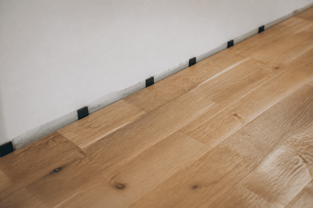 Lames de parquet posees le long du mur avec espacement