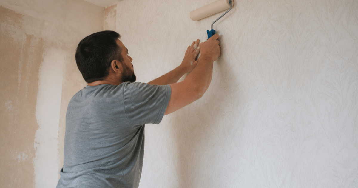 Ouvrier colle papier peint mur vertical avec rouleau