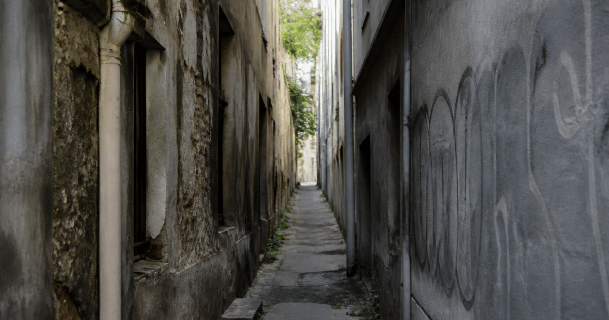 rue étroite avec immeubles dégradés et graffitis sur murs gris