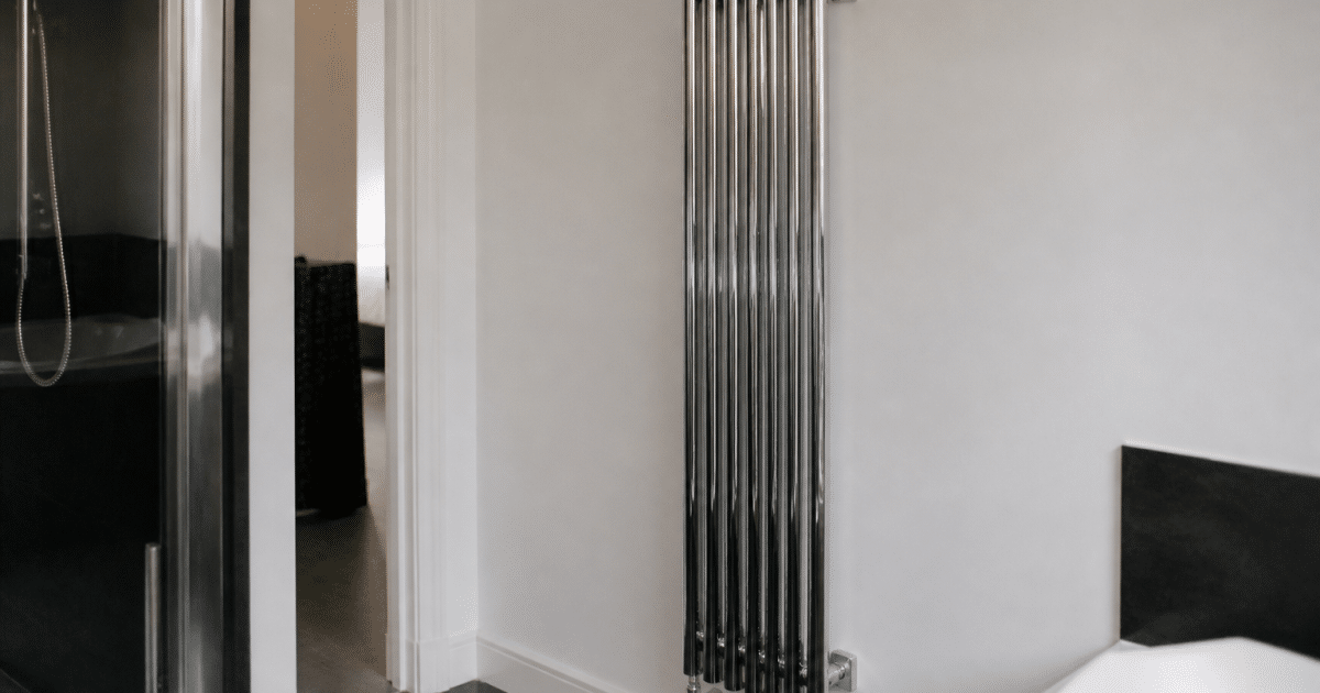 Radiateur chrome vertical fixe au mur blanc salle bain
