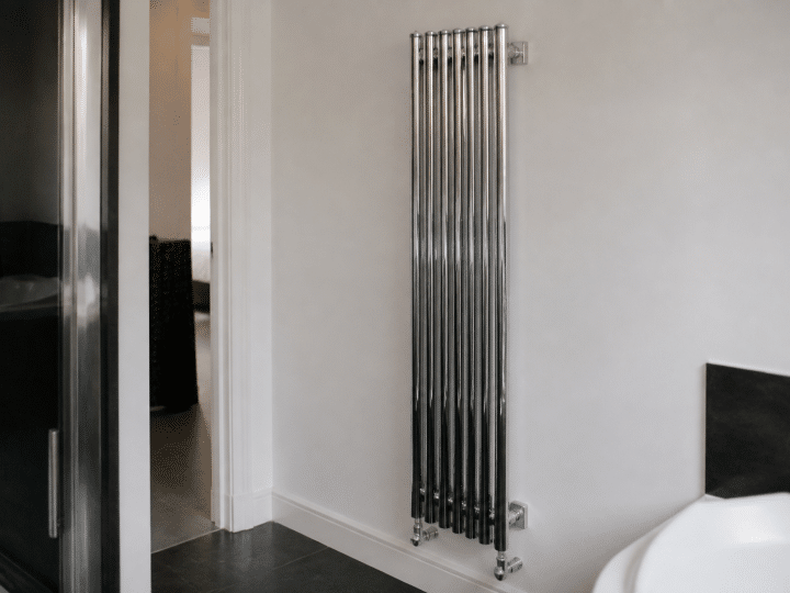 Radiateur chrome vertical fixe au mur blanc salle bain