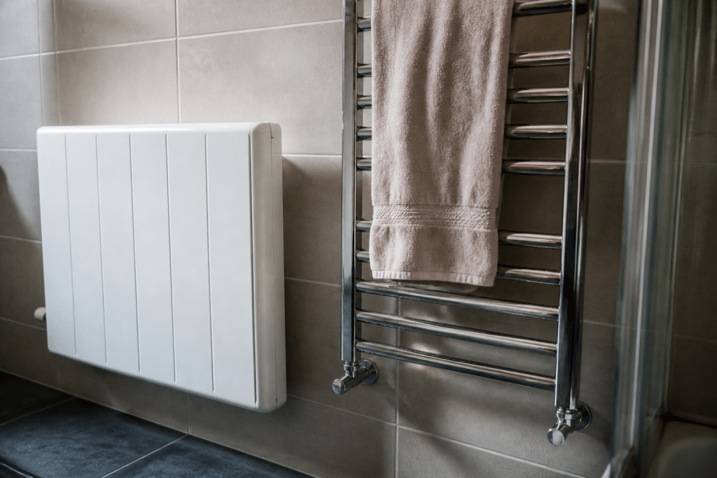 Radiateur blanc et porte-serviettes chromé dans salle de bain carrelée
