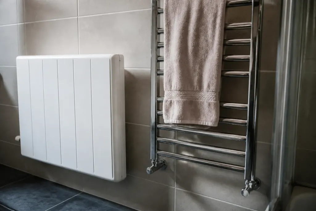 Radiateur blanc et porte-serviettes chromé dans salle de bain carrelée