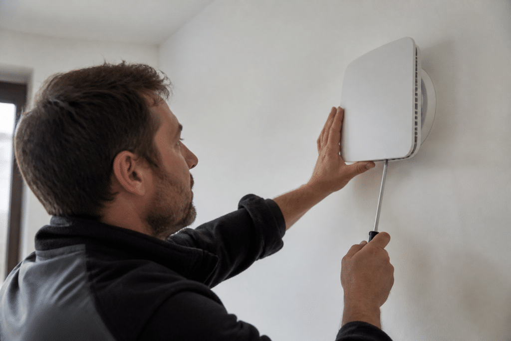 Installateur fixant boitier ventilation murale blanc moderne