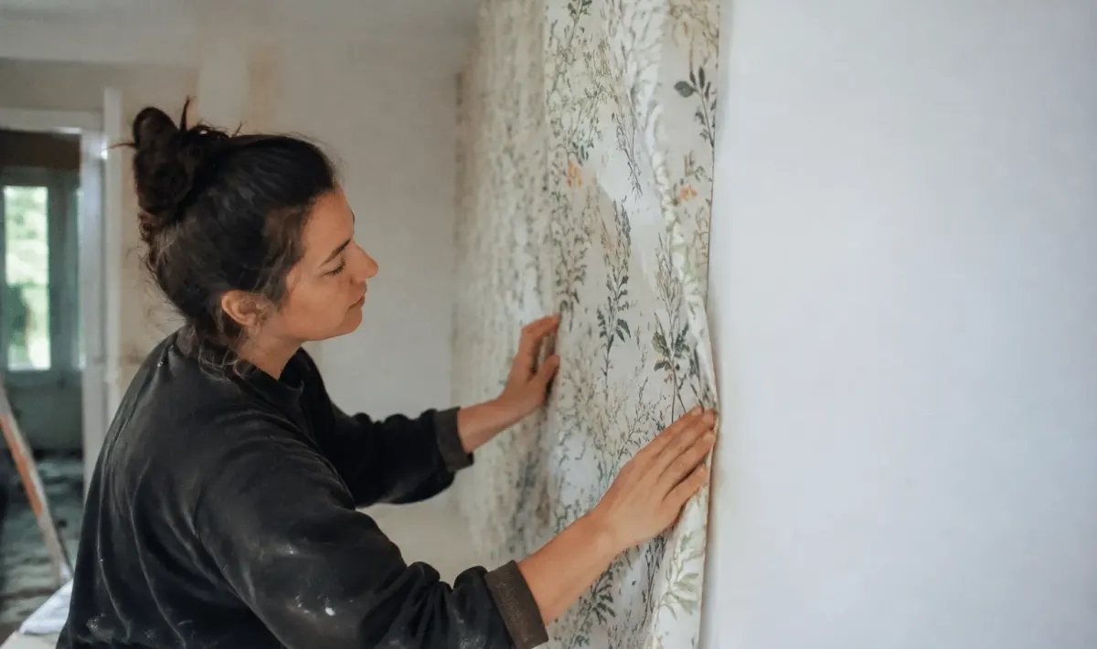 main appliquant papier peint sur angle convexe de mur blanc