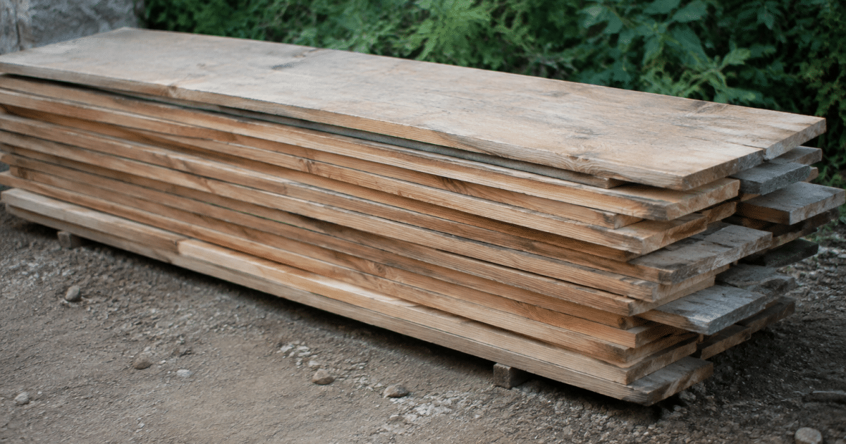 Planches bois empilees horizontalement sur sol nu