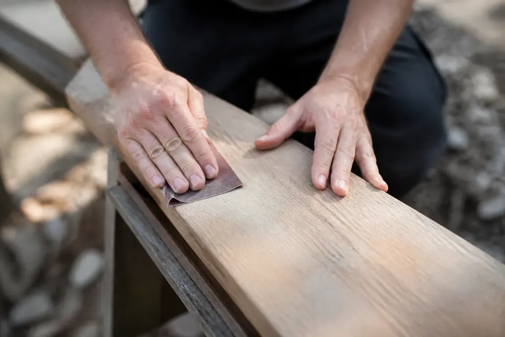 Mains poncant une planche avec papier de verre