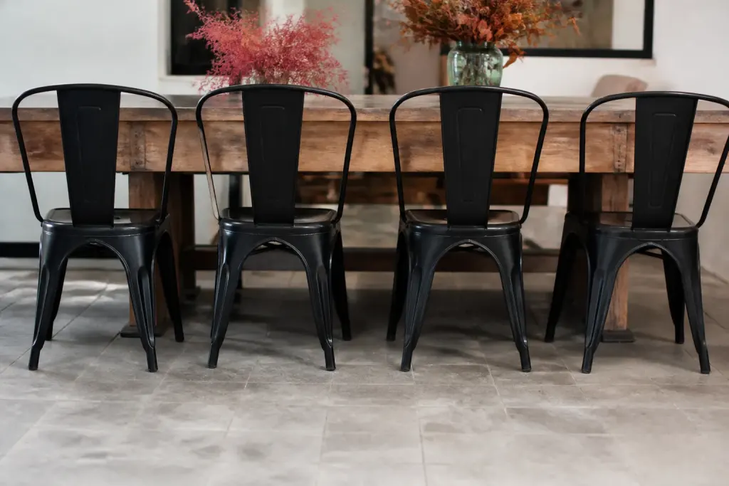 Quatre sieges metal noir mat alignes devant table bois