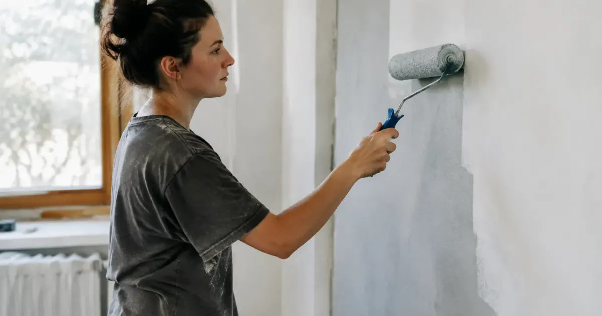 Personne debout applique peinture rouleau surface mur vertical